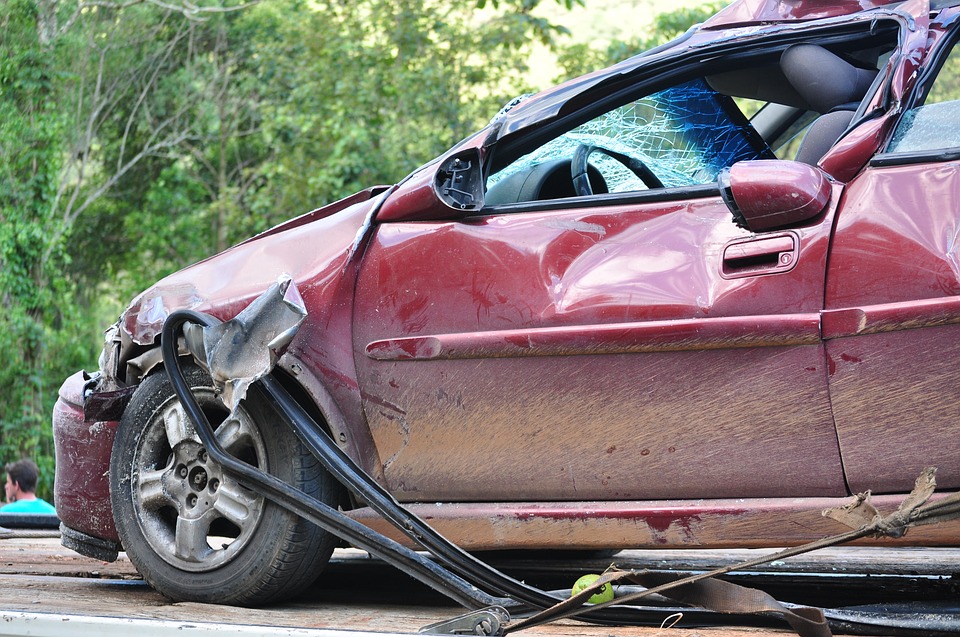 Damaged vehicle with emergency response lights in the background